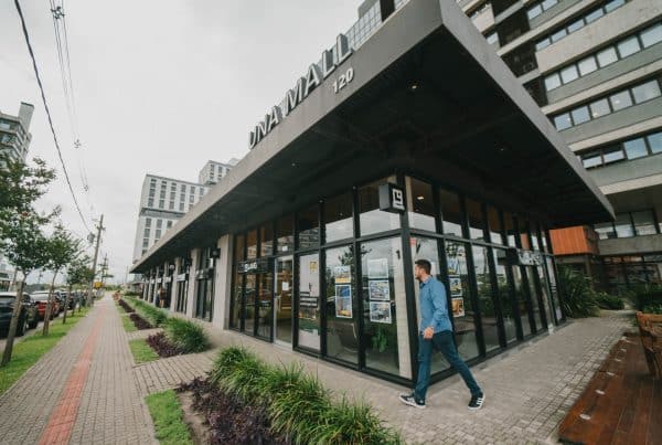 Imagem do UNA Mall, um hub corporativo moderno, com fachadas de vidro e a presença de pedestres na área externa, localizado no Parque Una Pelotas