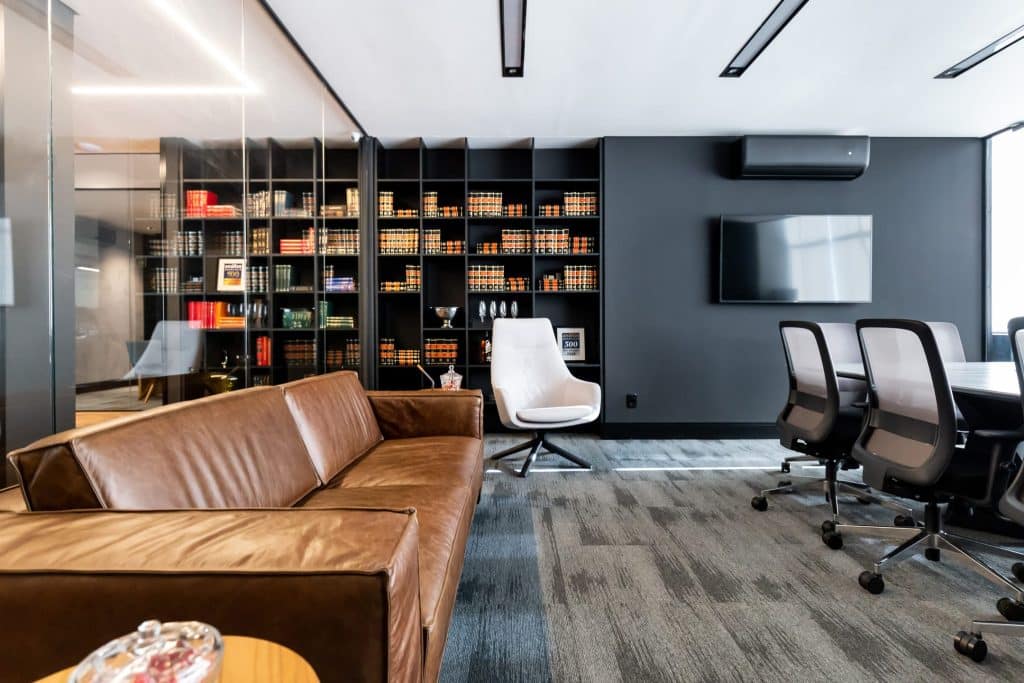 Imagem de um ambiente moderno de escritório, com uma mesa de reuniões elegante e prateleiras repletas de livros, transmitindo um espaço sofisticado e profissional para a sede de uma empresa.